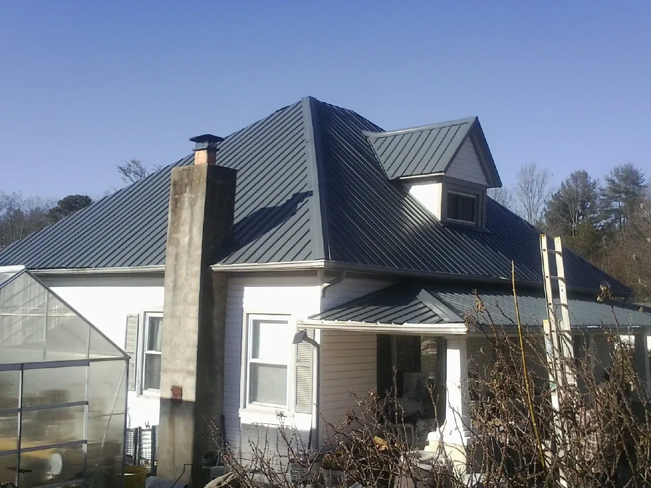 Dark blue standing seam metal roof on a white farmhouse with dormer — Slate & Tile Roof Repair by Roofing Brothers in Eloy