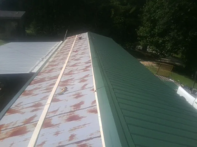 Old rusted panels beside newly installed green metal roofing — Wind Damage Roof Repair by Roofing Brothers in Eloy