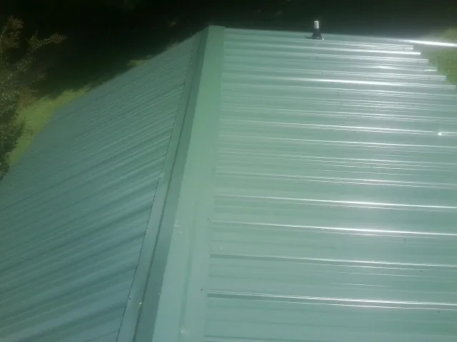 New green metal panels meeting at the ridge of a roof — Flat Roof Repair work by our crew in Eloy