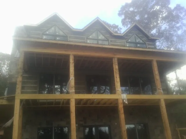 Dormers and porch framing on a large log home under construction — Roof Coating work by our crew in Eloy