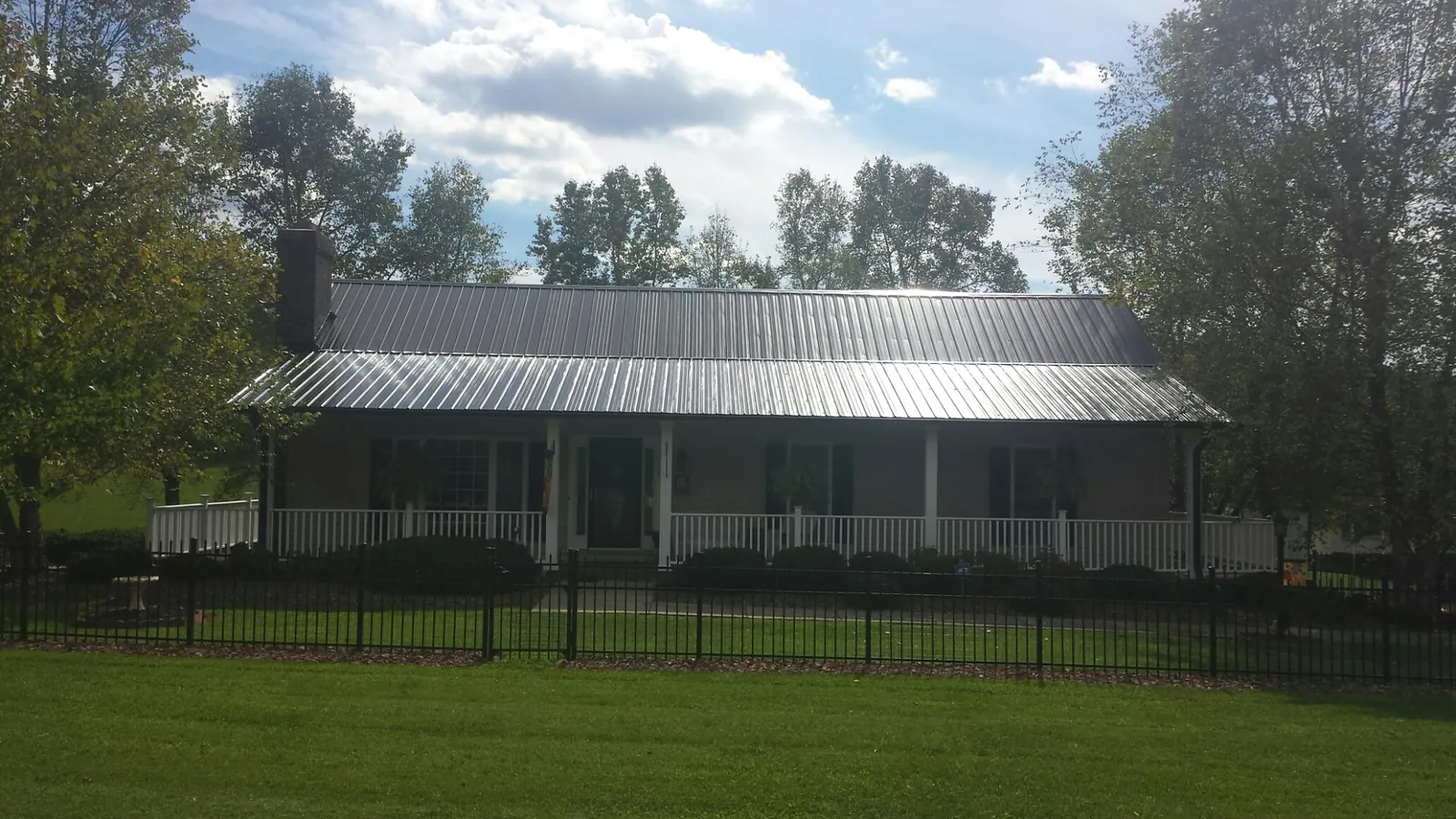 Gray metal roof on a brick ranch with a full width front porch — Gutter Guard Installation work by our crew in Eloy