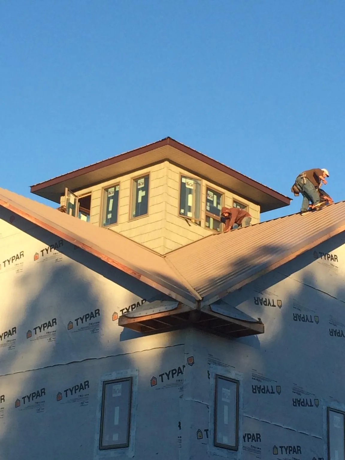 Roofers working around a rooftop cupola on a new metal roof at sunset — Roof Waterproofing in Eloy by Roofing Brothers